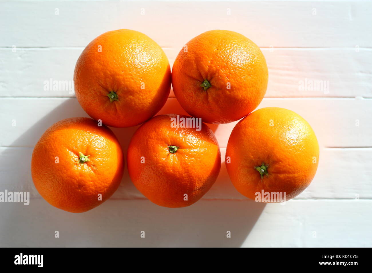 Fünf süßen Orangen auf einem weißen Tisch, Kontrast aus dem Licht der Sonne Stockfoto