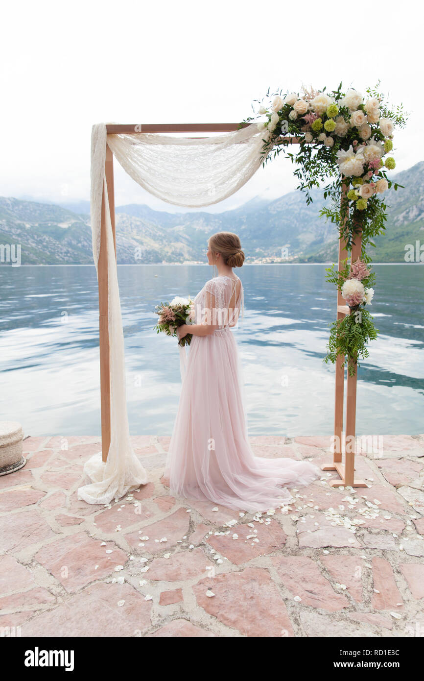 Schöne hölzerne Hochzeit Bogen mit Blumen im Freien und die Braut eingerichtet Stockfoto