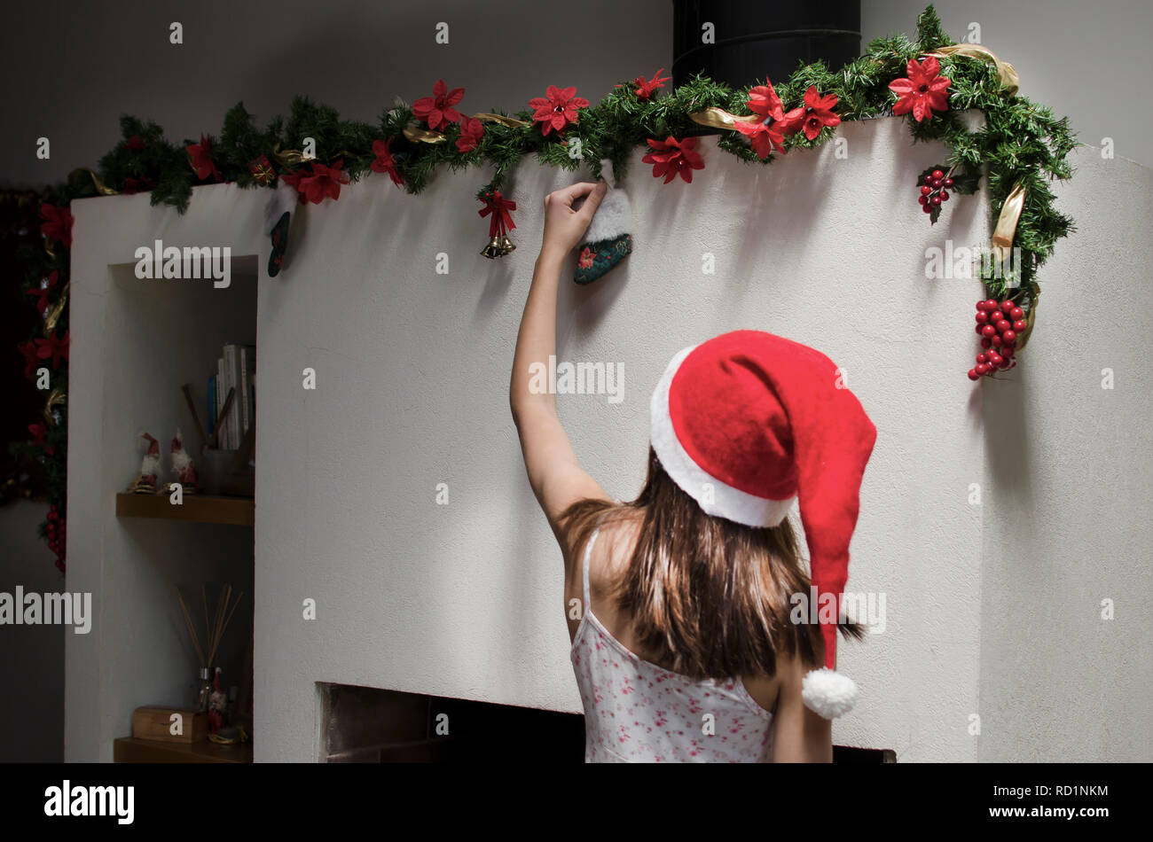 Mädchen hingen Weihnachtsdekorationen über einem Kamin Stockfoto