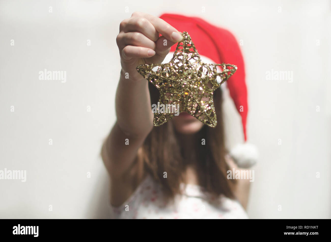 Mädchen mit einem Santa Hut Holding a Christmas Star Dekoration Stockfoto