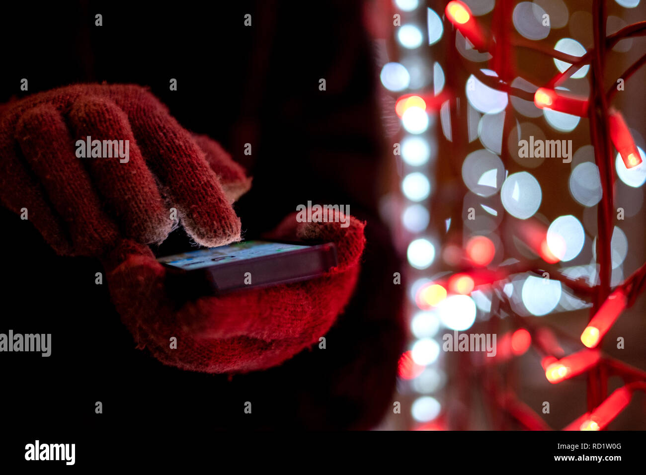 Frau mit Handschuhen können Sie über Ihr Mobiltelefon bei Nacht Stockfoto