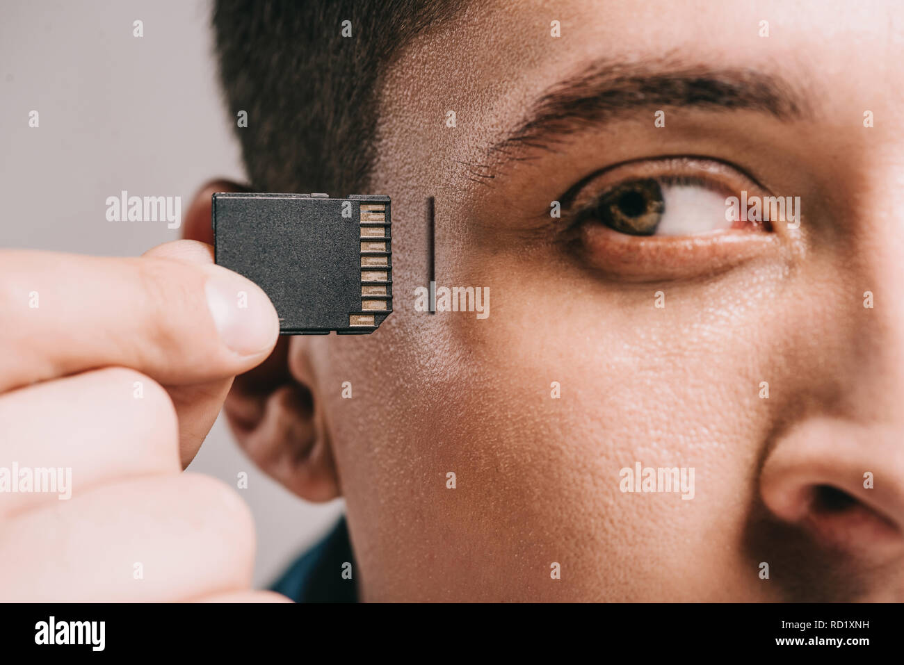 Nahaufnahme der Mann Implantation Microchip im Kopf auf Grau isoliert Stockfoto