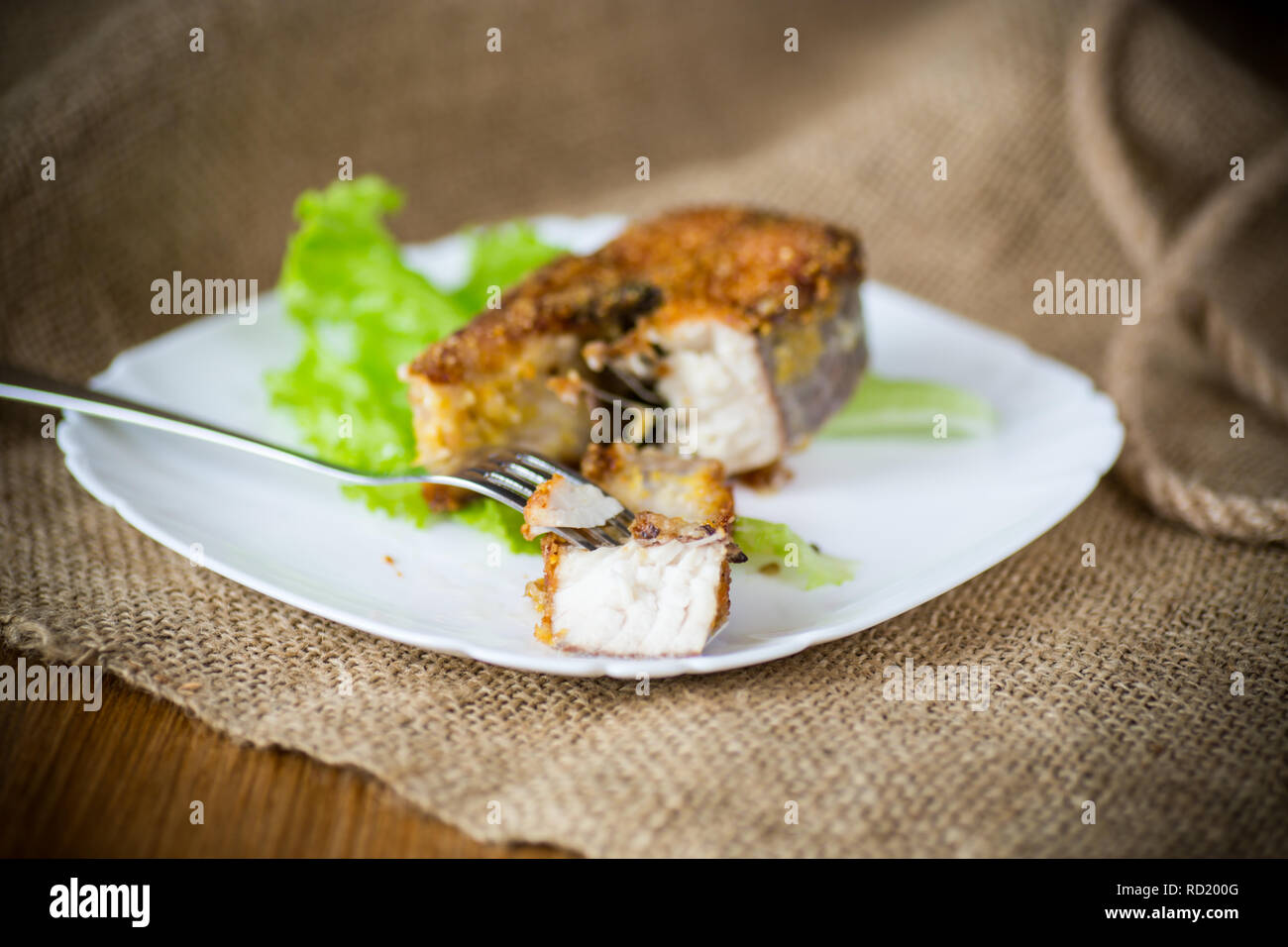 Stück gebratener Fisch in einer Platte auf einer hölzernen Stockfoto