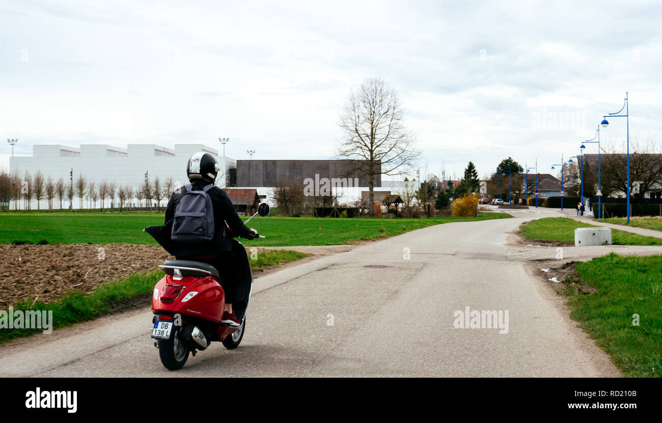 Straßburg, Frankreich - Apr 2, 2018: Junge unbekümmerte Frau reiten Italienische Vespa Primavera 5 rote Roller auf einer Landstraße in der Nähe von Straßburg Stockfoto