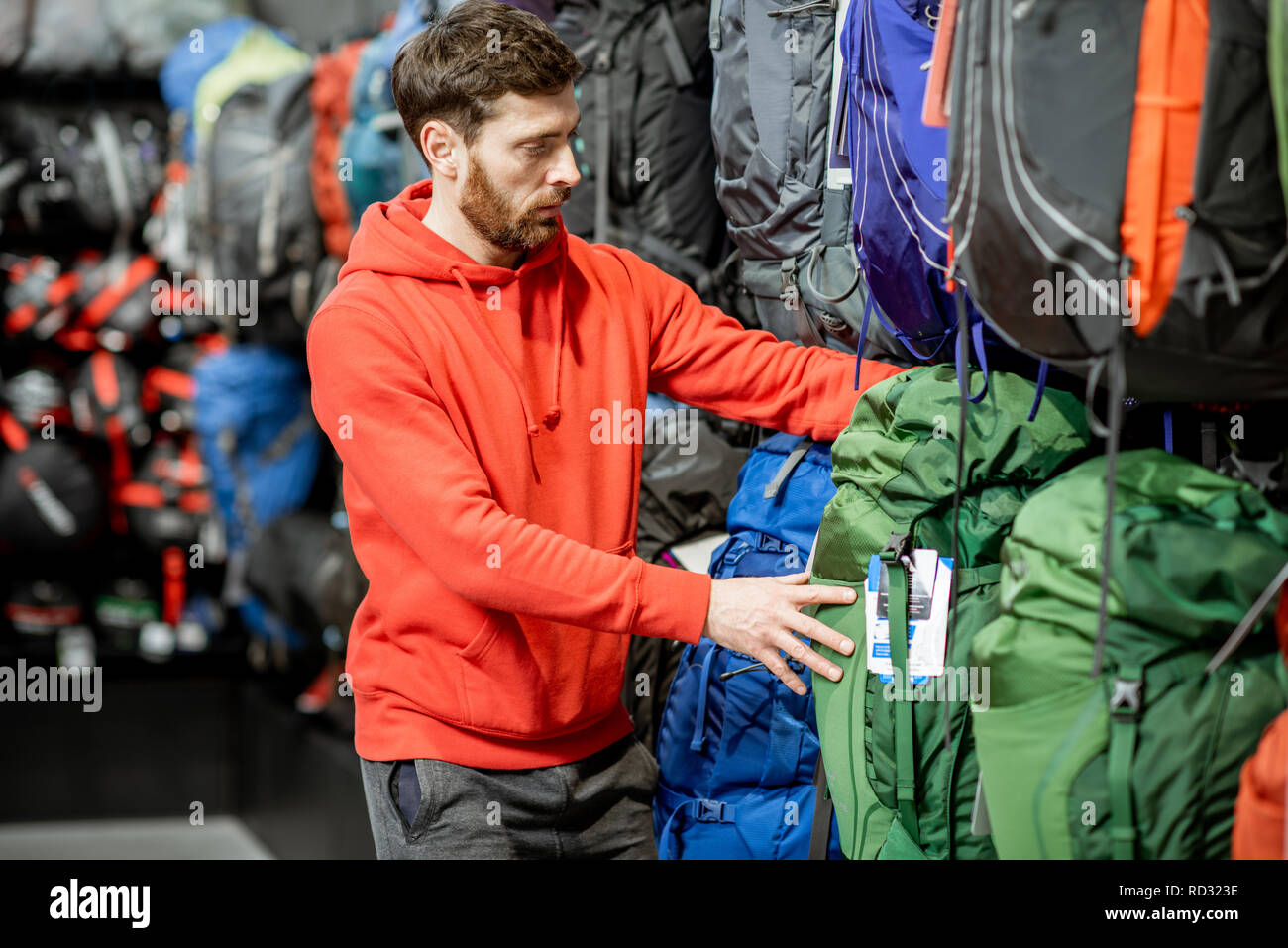Mann der Wahl einige Sportgeräte suchen auf die Rucksäcke für Reisen im Sport Shop Stockfoto