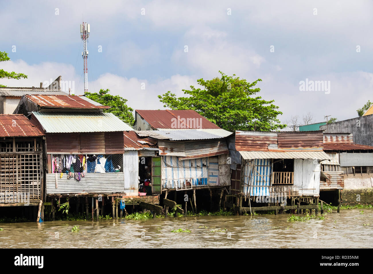 Typische Vietnamesische tin shack Pfahlbauten am Ufer des Hau Flusses. Can Tho, Mekong Delta, Vietnam, Asien Stockfoto
