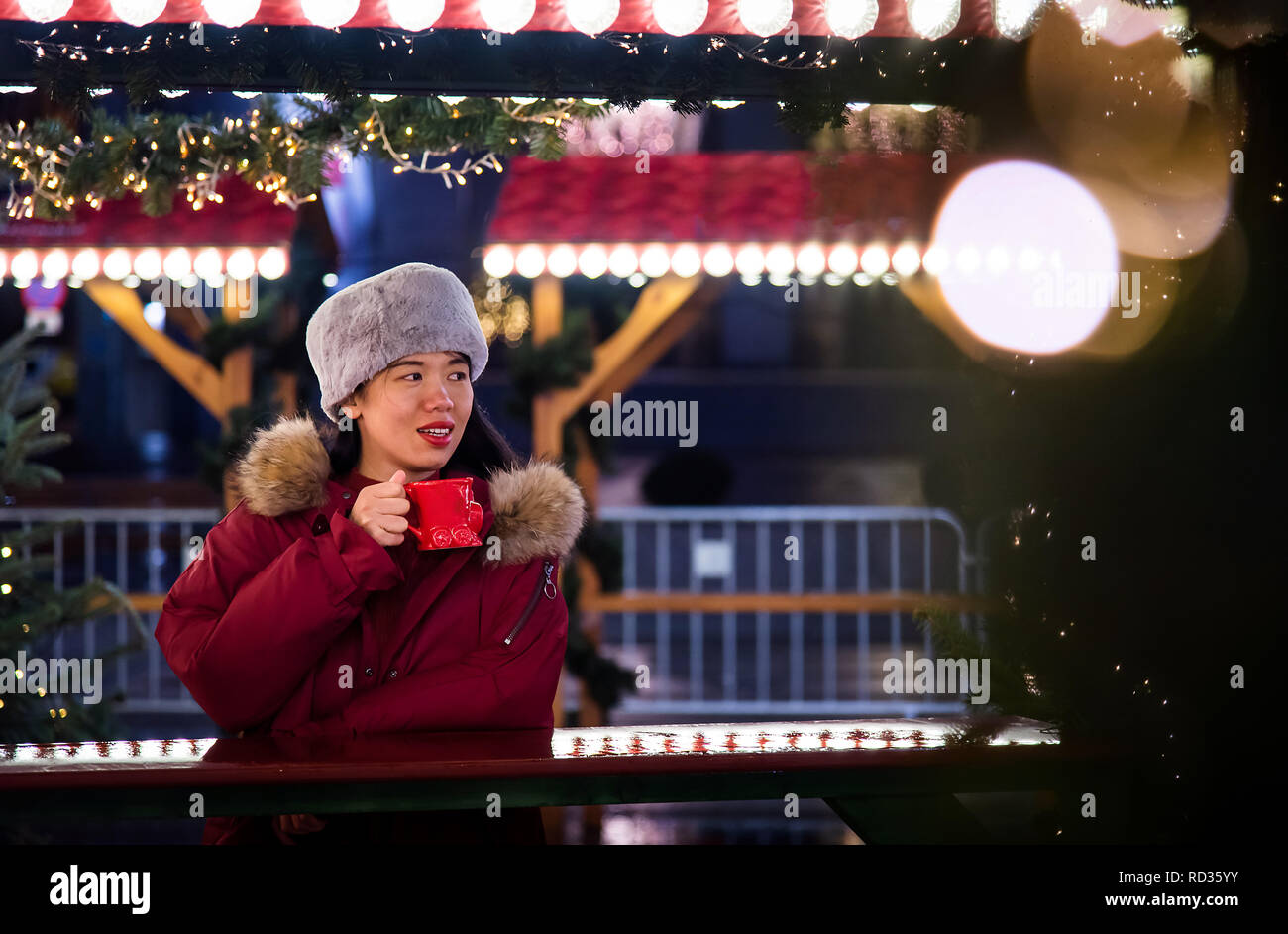 Frau mit einem warmen Getränk außerhalb in einer Winternacht Stockfoto