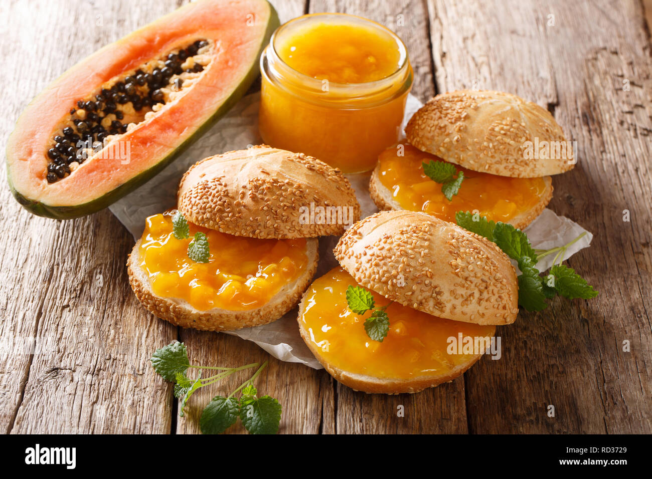 Frühstück, Brötchen mit Papaya Marmelade, Frischkäse und Minze close-up auf dem Tisch. Horizontale Stockfoto