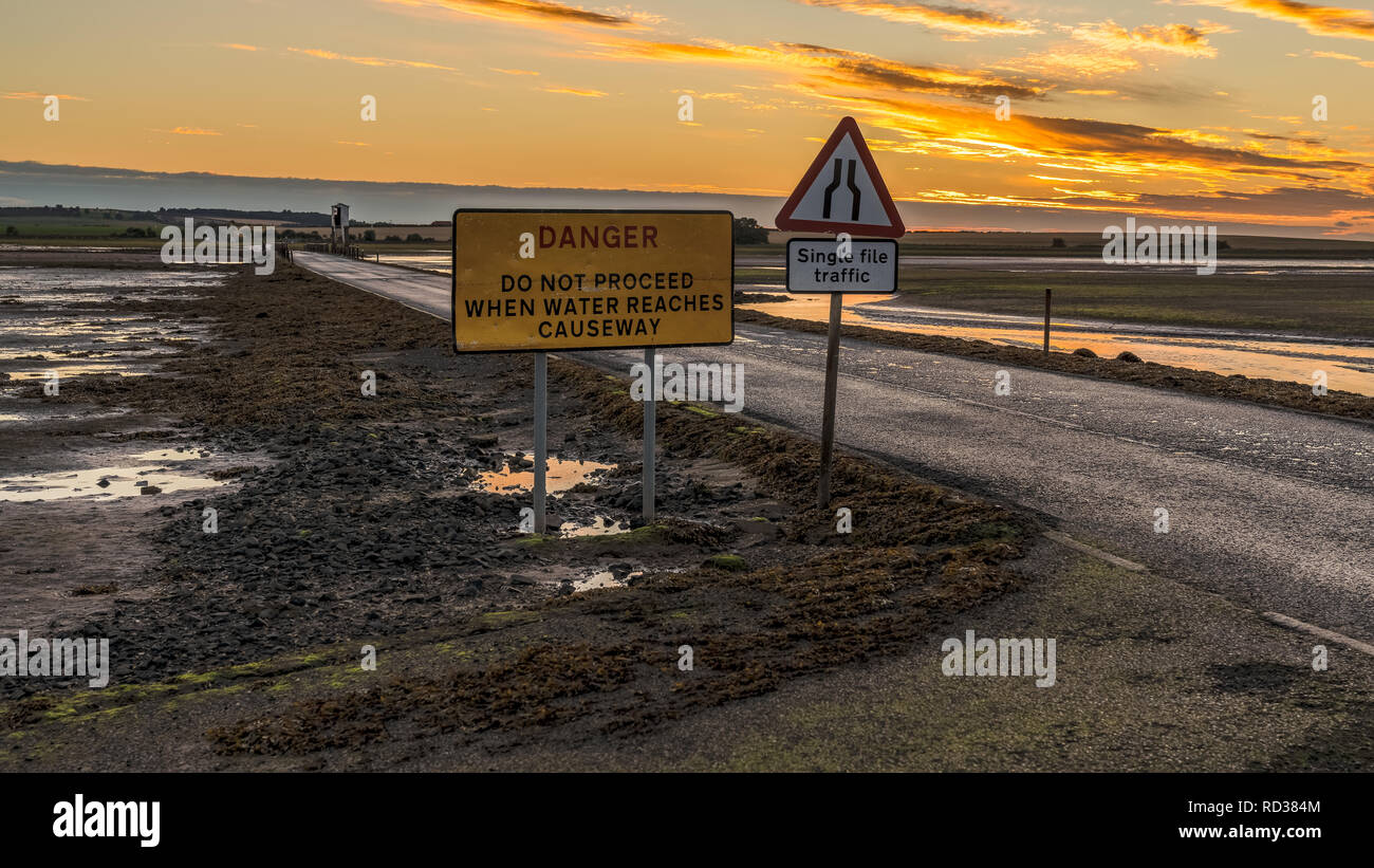 Zeichen: Einzelne Datei Verkehr, Gefahr, fahren Sie nicht fort, wenn Wasser Causeway erreicht, an der Straße zwischen Beal und Heilige Insel in Northumberland, England gesehen Stockfoto