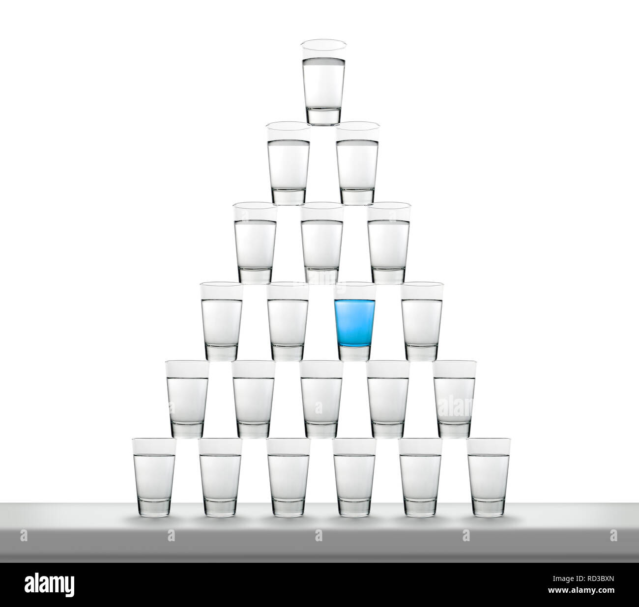 Pyramide von Wassergläsern, eines mit blauer Flüssigkeit Stockfoto