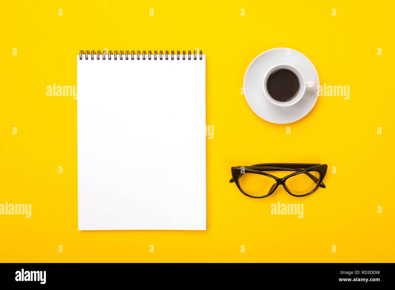 Arbeitsbereich mit Notebook, Gläser und Tasse Kaffee am Morgen auf gelbem Hintergrund Stockfoto
