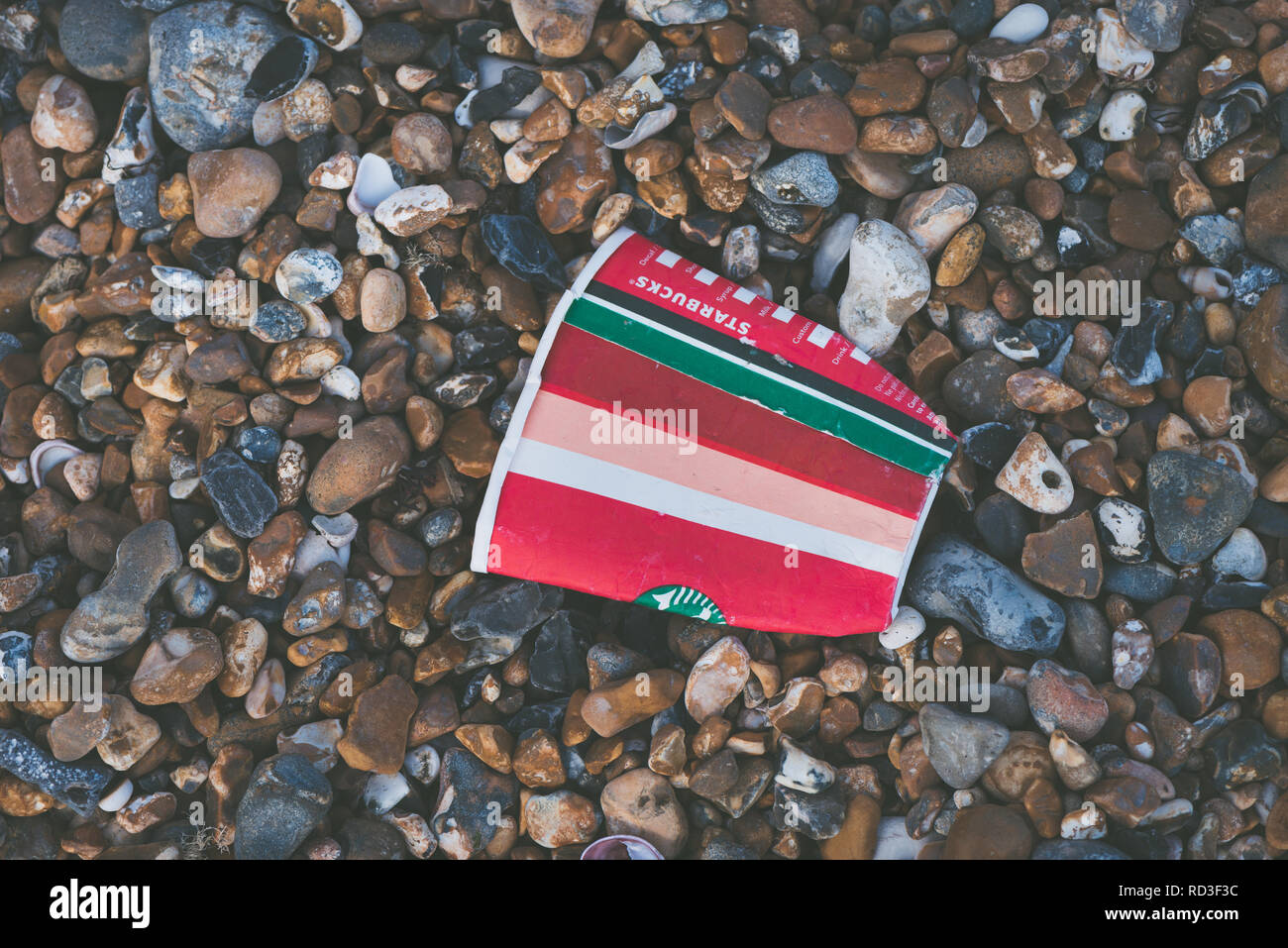 Wurf auf den Strand. Eine weggeworfene Starbucks Coffee Cup an einem Kieselstrand. Stockfoto