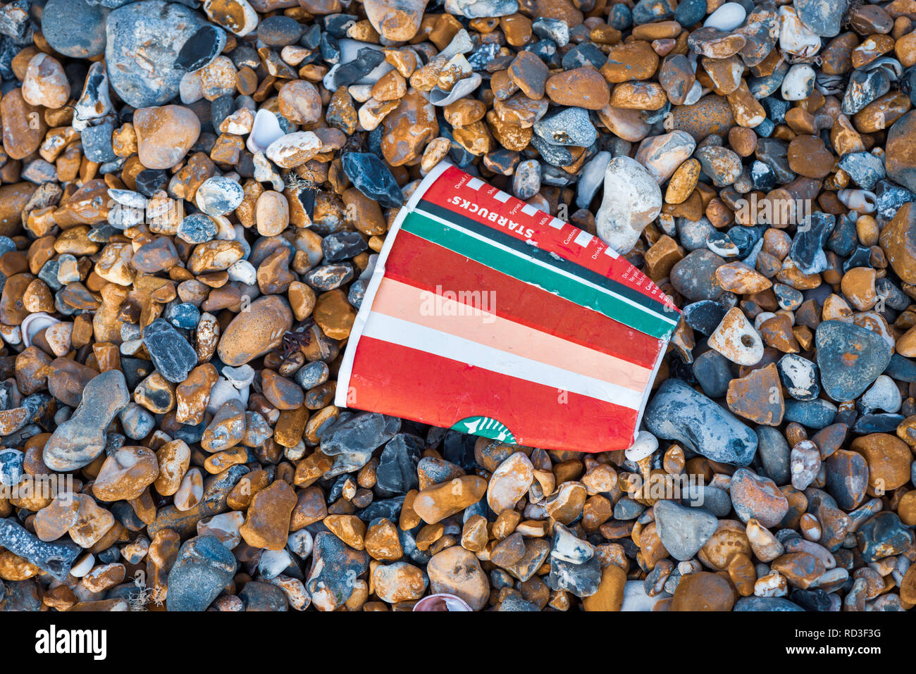 Wurf auf den Strand. Eine weggeworfene Starbucks Coffee Cup an einem Kieselstrand. Stockfoto