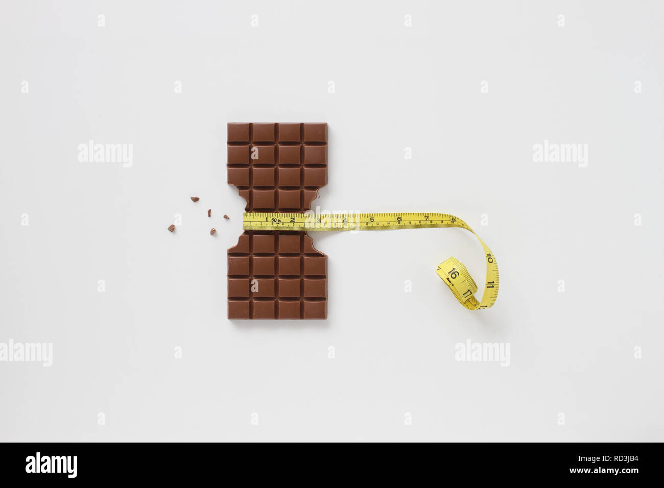 Block von Schokolade mit Seiten überfordert und Schokolade Krümel mit einem Maßband um die Mitte Stockfoto