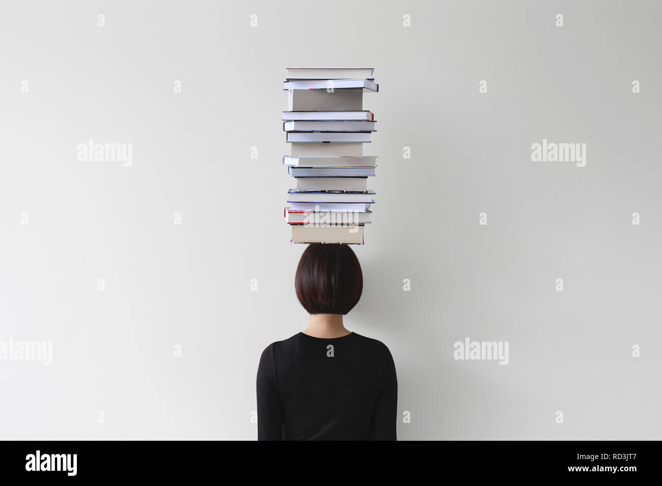 Ansicht der Rückseite Frau mit Stapel Bücher auf dem Kopf Stockfoto