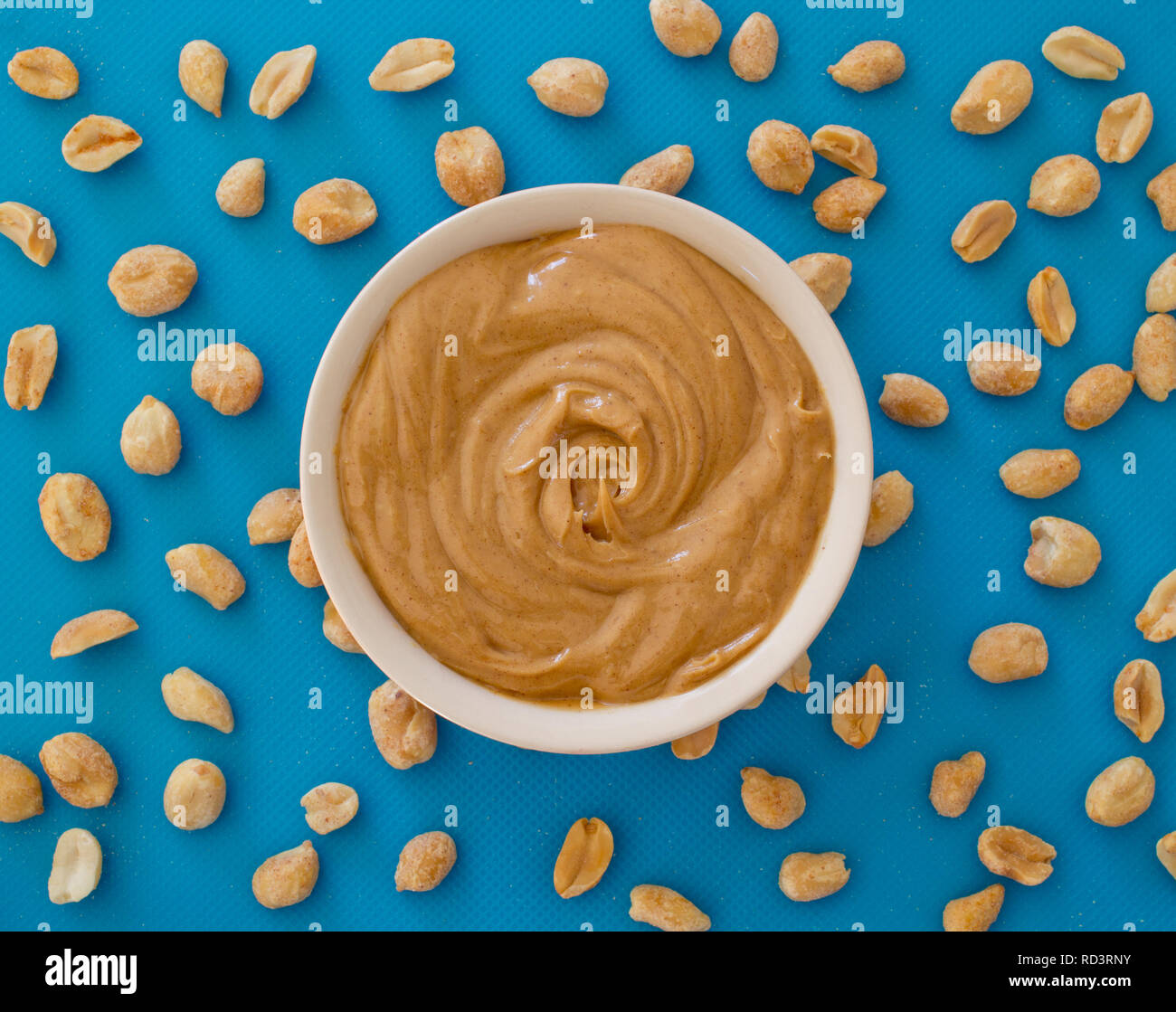 Weiche und cremige Erdnussbutter und Erdnüsse auf Blau. Von oben nach unten anzeigen. Stockfoto
