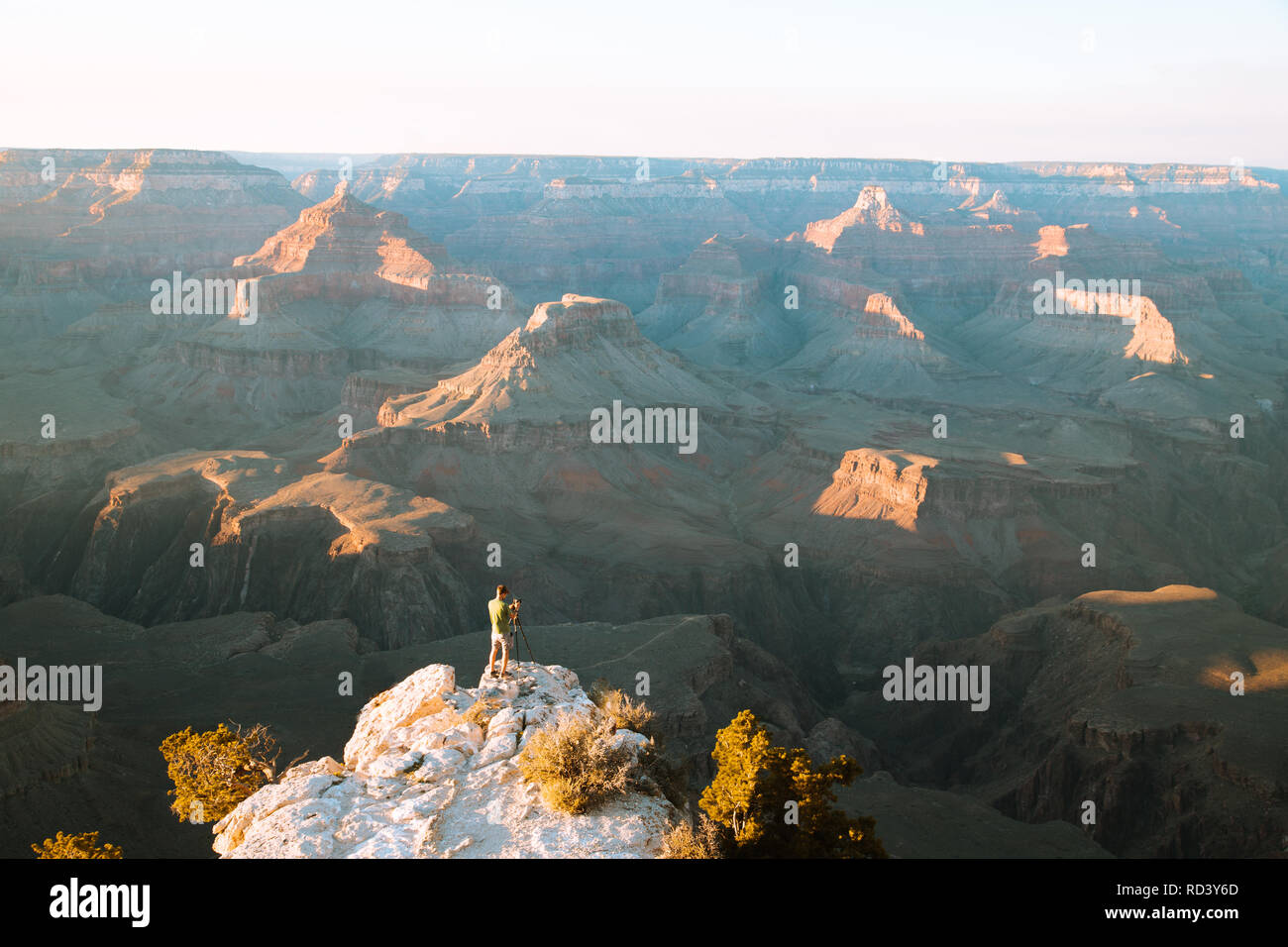 Ein männlicher Fotograf steht auf einer Klippe mit Blick auf den berühmten Grand Canyon National Park bei Sonnenuntergang, Amerikanischen Südwesten, USA Stockfoto
