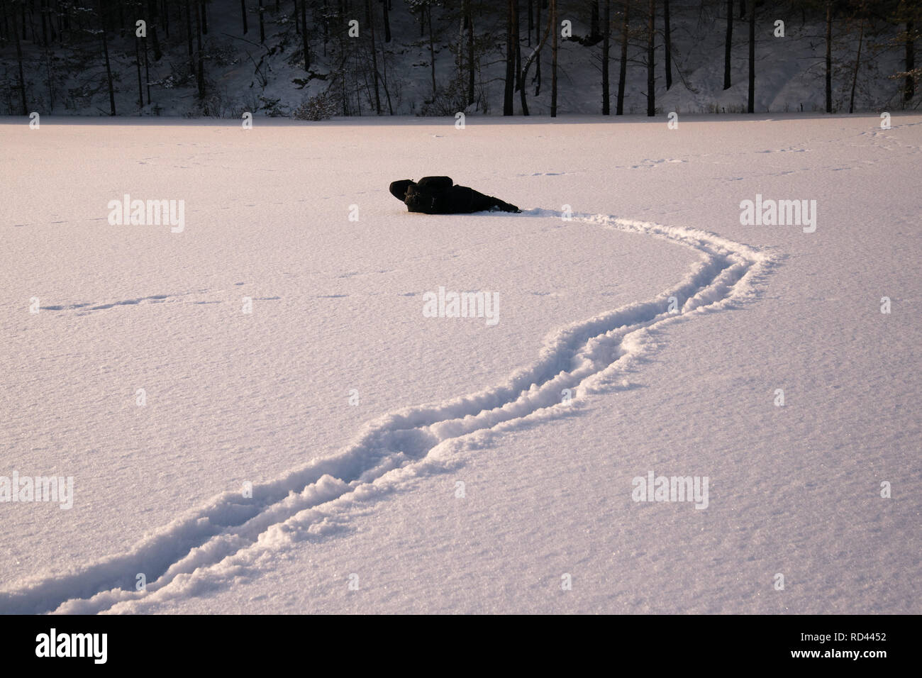 Ein einsamer Mann, Spaziergänge im Schnee. Dramatische Silhouette eines Mannes zu Fuß in einer verschneiten Lichtung im Wald. Kalt. Stockfoto