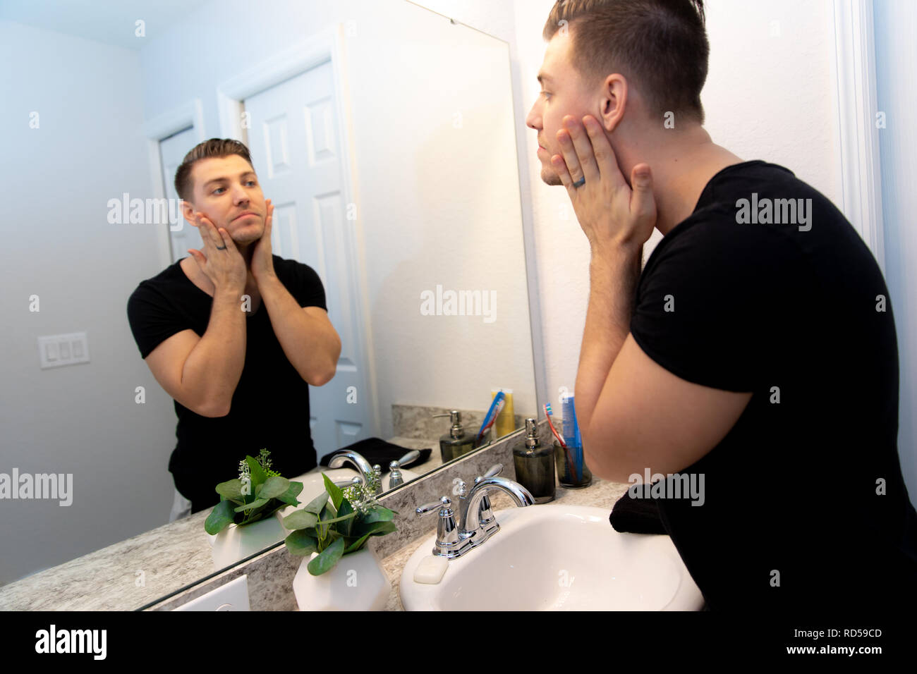 Gut aussehende junge Mann Waschen der Hände und Gesicht in Home Badezimmer Spiegel und Waschbecken Erhalten sauber und gepflegte Während der morgendlichen Routine Stockfoto