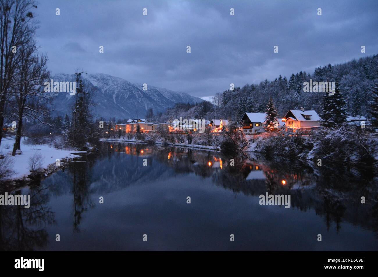 Kleine Häuser mit Schnee und chtistmas Lichter im malerischen Bad Goisern, Hallstatt abgedeckt. Nightfall Ansicht vom Fluß. Stockfoto