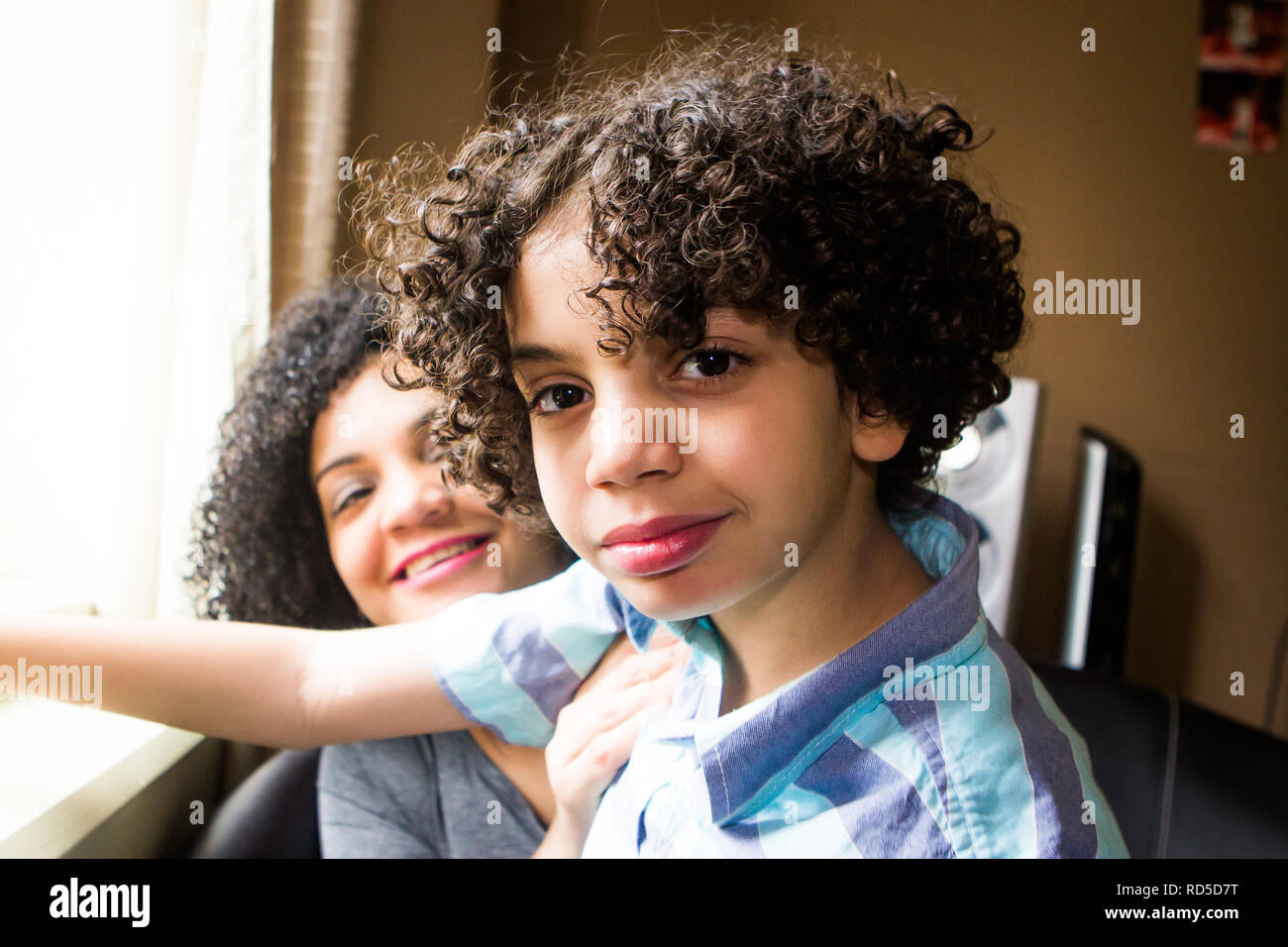 Nahaufnahme der autistischen Hispanic junge lächelt mit Mutter durch Fenster Stockfoto