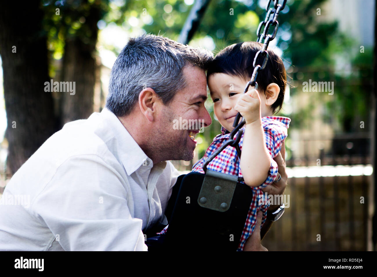 Weiß Vater liebevoll Biracial asiatischen Sohn auf Swing Stockfoto