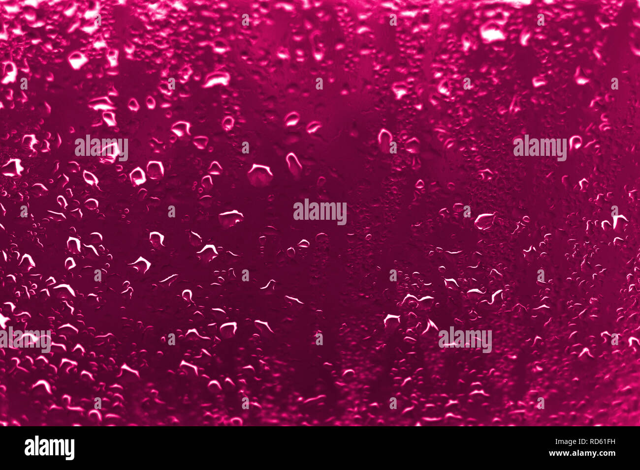 Hoher Kontrast Foto von Regentropfen auf einem Fenster Glas mit lebhafter rötlich rosa Farbe Stockfoto