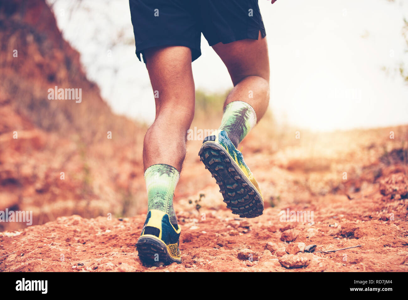 Ein Mann Runner von Trail. Und in der Nähe der Füße tragen ein Athlet Sport Schuhe für Trail Running in den Bergen Stockfoto