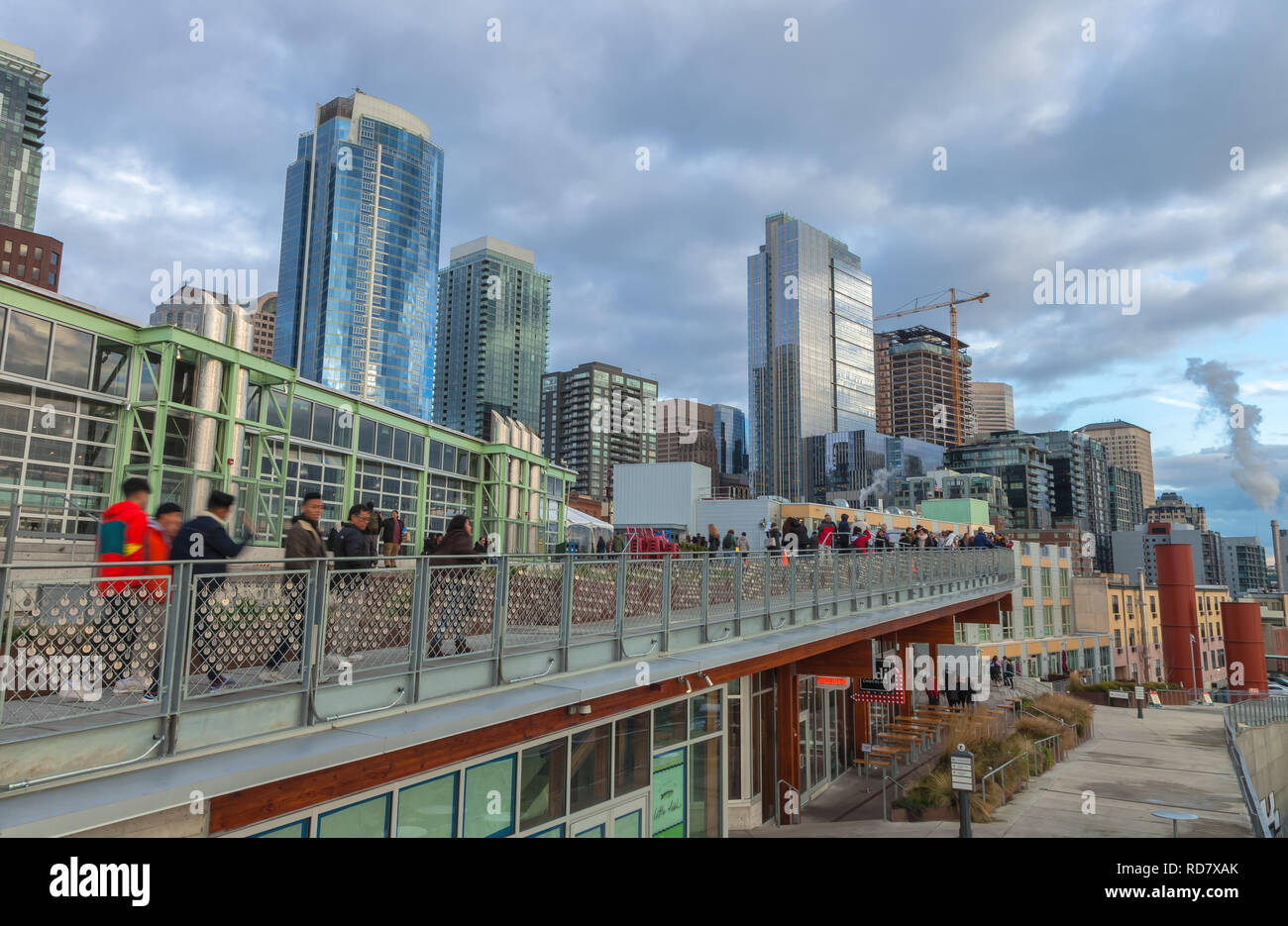 Ansicht Deck hinter den Pike Place Markt mit Touristen mit Blick auf die Elliot Bay, gefüllt mit Downtown Seattle im Hintergrund, Washington, United States. Stockfoto