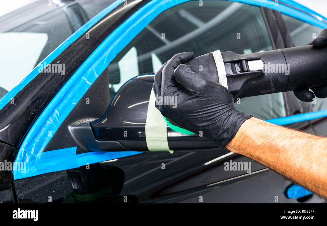 Auto politur Wachs Arbeiter Hände Anwendung Schutzfolie vor dem Polieren. Polieren und polieren Auto. Von Autoteilen. Mann hält eine poliermaschine in der Hand und Stockfoto