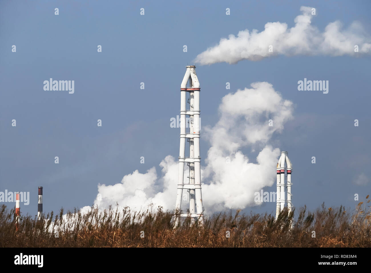 Industrielle Schornstein mit Rauch vor blauem Himmel Stockfoto