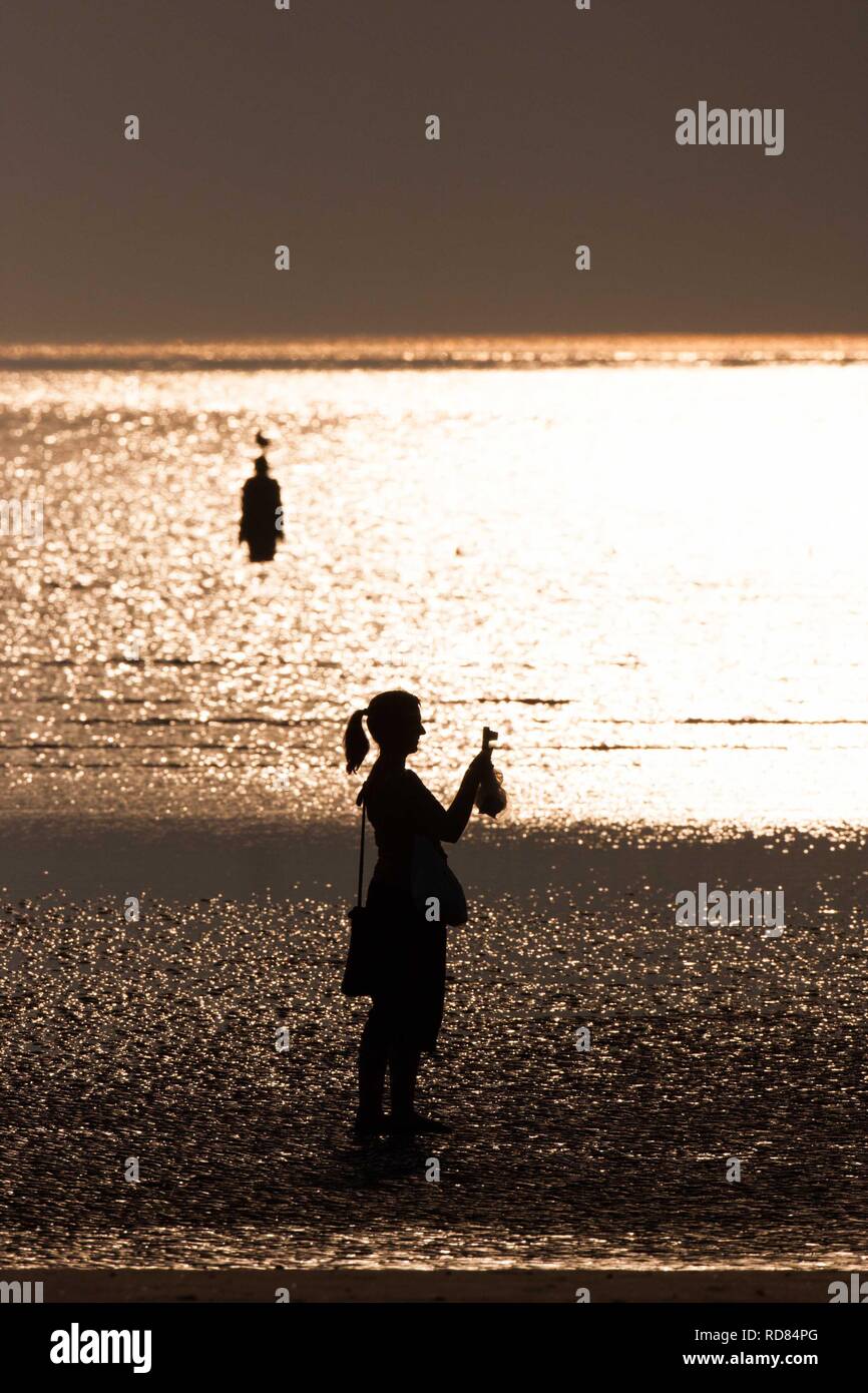 Silouhette von Sir Antony Gormley, einem anderen Ort Skulpturen auf Crosby Strand, Touristen Skulpturen fotografieren. Stockfoto