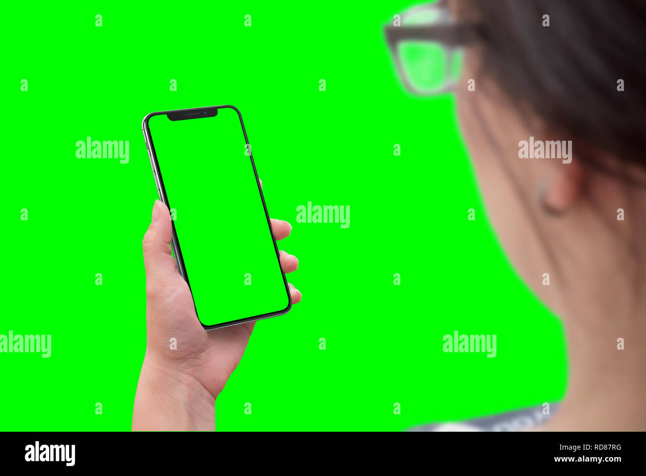 Frau mit modernen smart phone mit runden Kanten. Isolierte Bildschirm für die Modellerstellung und Hintergrund in grün, Chroma Key. Stockfoto