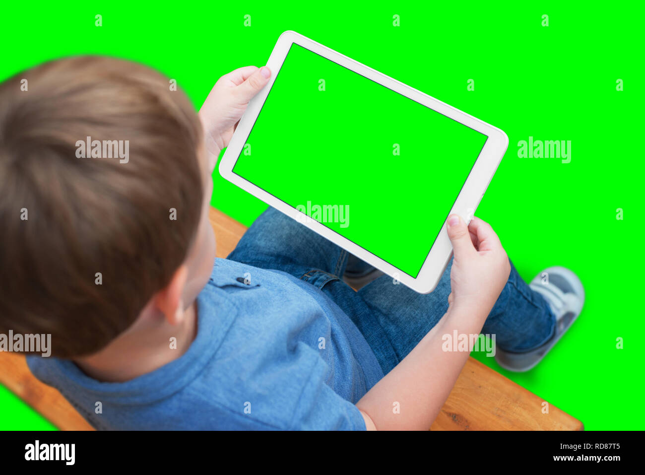 Jungen spielen oder Videos auf weiße Tablette. Isolierte Bildschirm und Hintergrund in grün, Chroma Key. Stockfoto