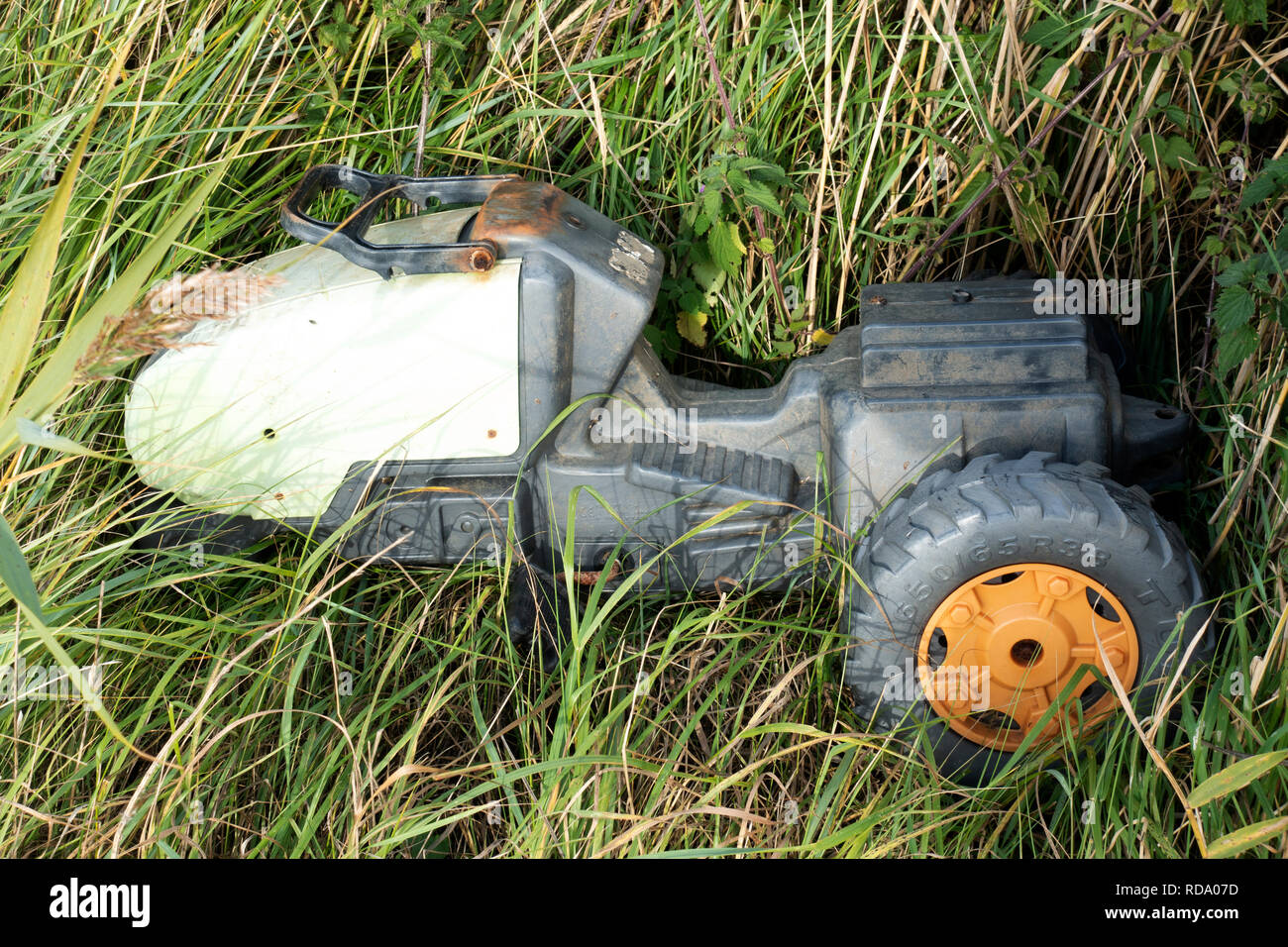 Brocken Childrens Ride-on Traktor gedumpten am Straßenrand Stockfoto