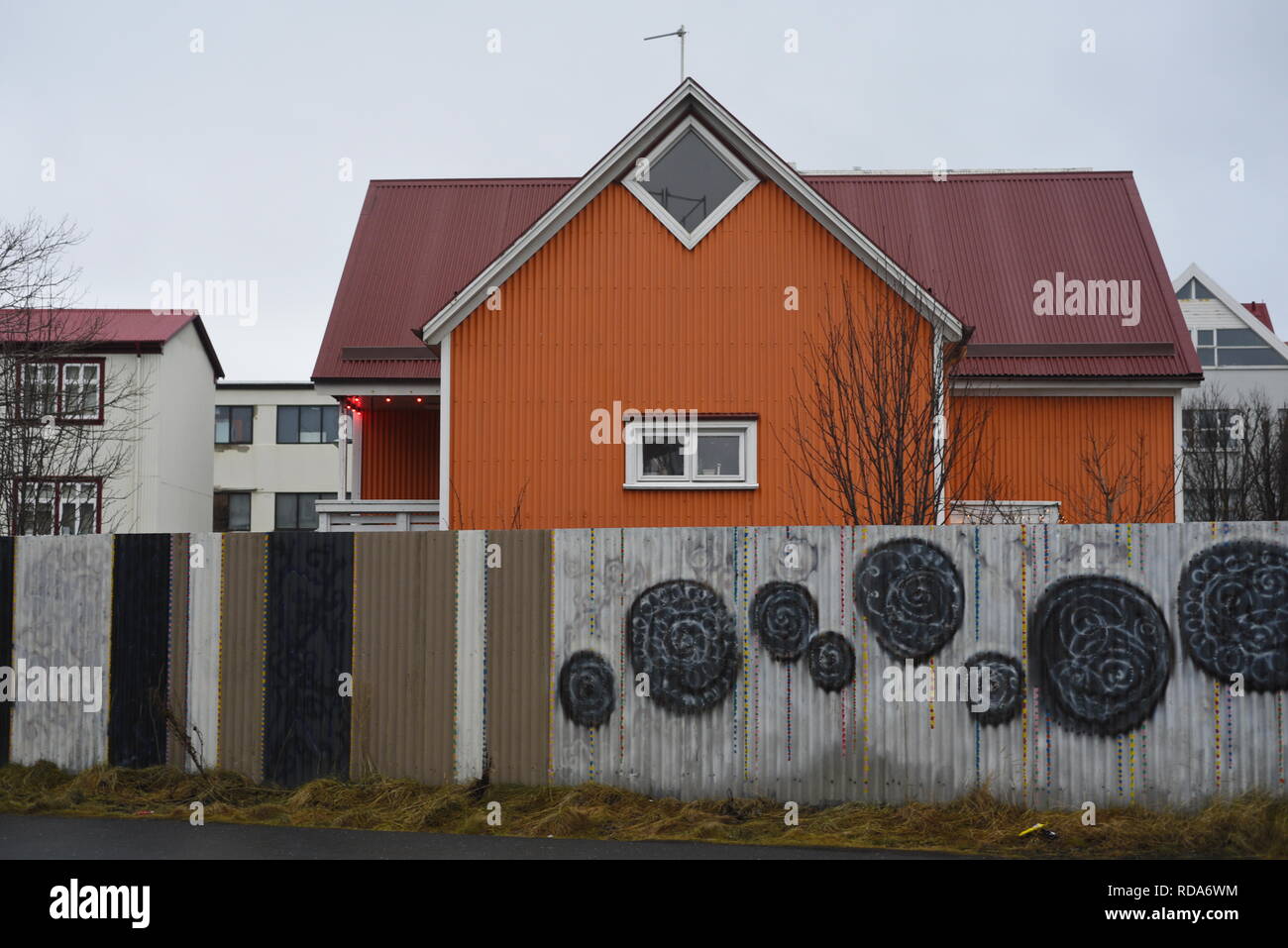 Orange House in Reykjavik, Island. Mit street art auf dem Zaun. Stockfoto