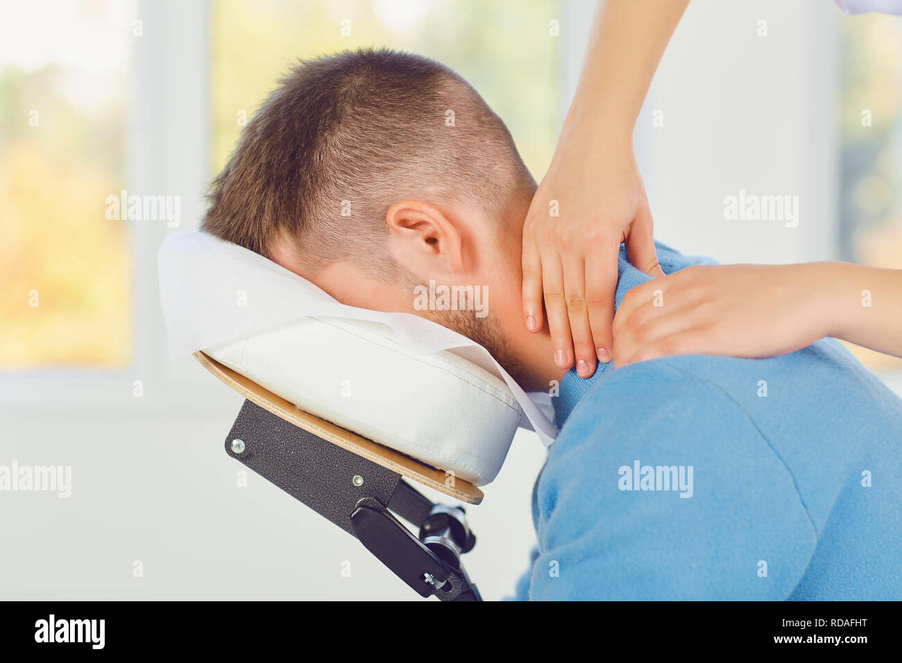 Massage auf dem Massagestuhl im Büro. Masseur die Massage zu einem Mann sitzt auf einem Massagestuhl in einer Klinik. Stockfoto