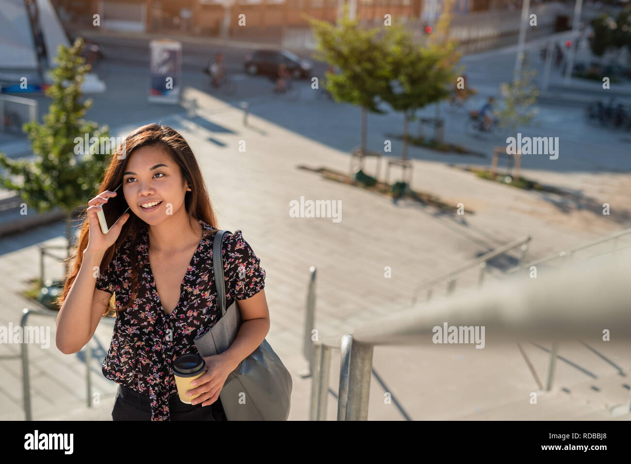 Lächelnd asiatische Studenten Wandern auf dem Campus im Gespräch über Ihr Mobiltelefon Stockfoto