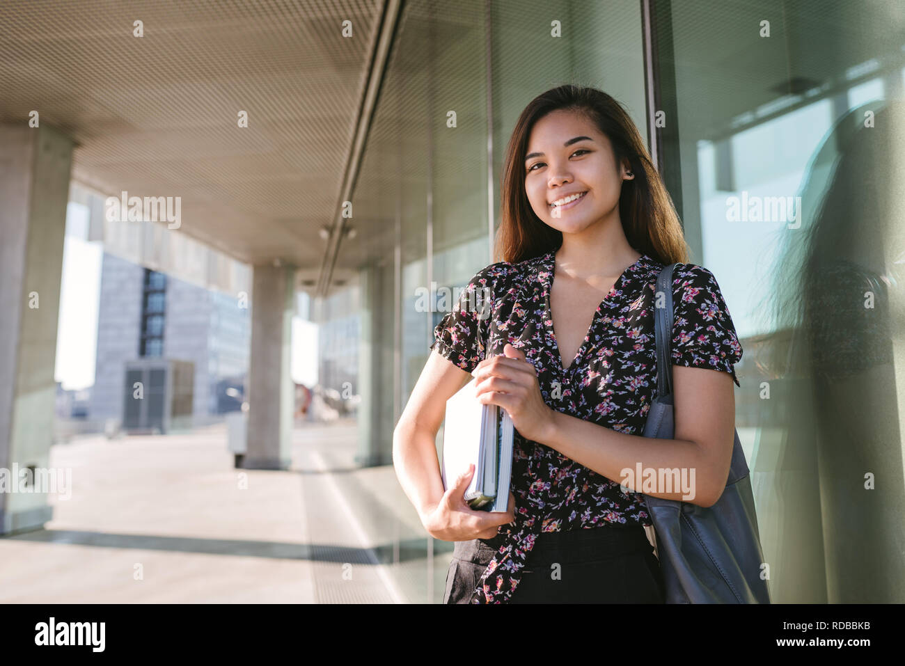 Junge asiatische Student selbstbewusst lächelnd beim Stehen auf dem Campus Stockfoto