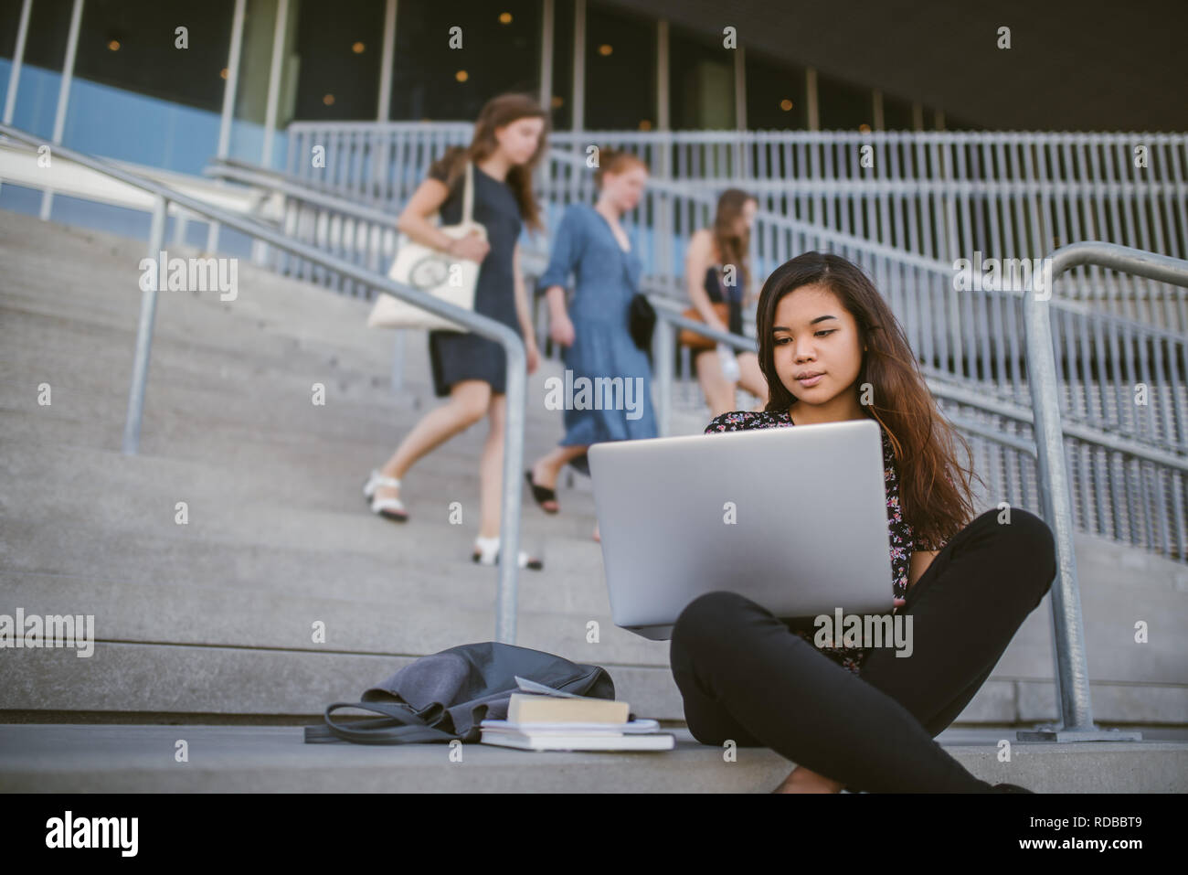 Junge asiatische Studenten sitzen auf dem Campus mit einem Laptop Stockfoto