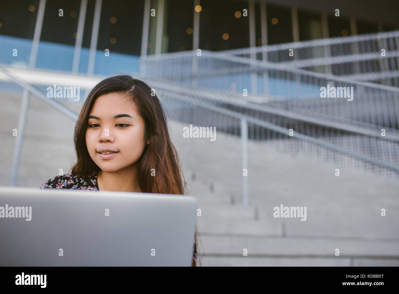Lächelnden jungen asiatischen Studenten ihre Hausaufgaben auf dem Campus Stockfoto