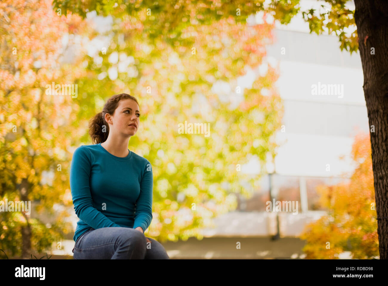 Ein junges Mädchen sitzen mit Herbstfarben im Hintergrund Stockfoto