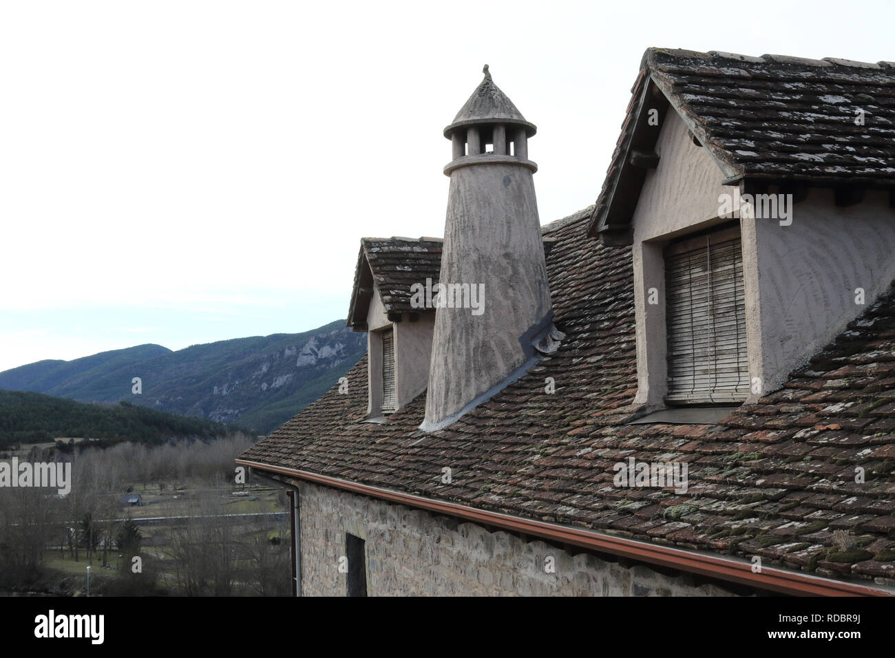 Ein traditionelles Haus dunklen Dach mit zwei Mansarde Windows, runde Schornstein in einem Pyrenäen Dorf im Winter in Hecho, Region Aragon, Spanien Stockfoto