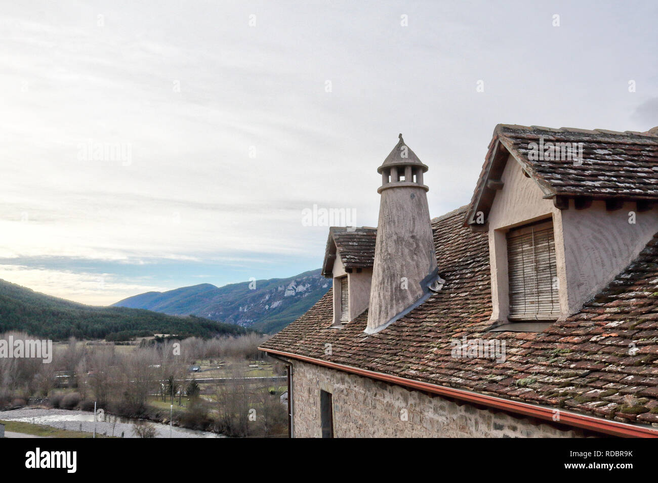 Ein traditionelles Haus dunklen Dach mit zwei Mansarde Windows, runde Schornstein in einem Pyrenäen Dorf im Winter in Hecho, Region Aragon, Spanien Stockfoto