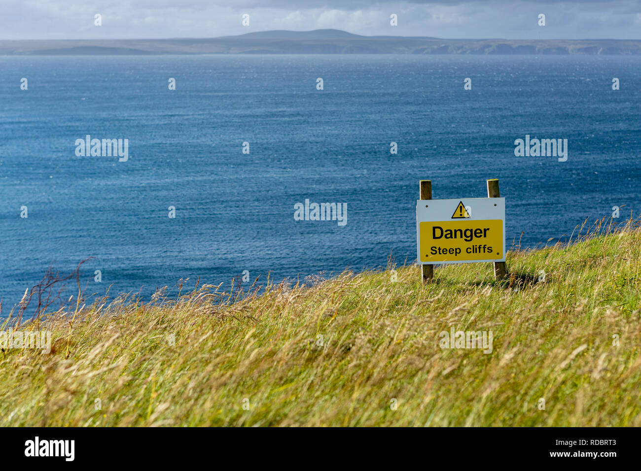 Warnschild auf steilen Felsen durch den Atlantischen Ozean, auf der Insel Lewis, Äußere Hebriden, Schottland, UK Stockfoto