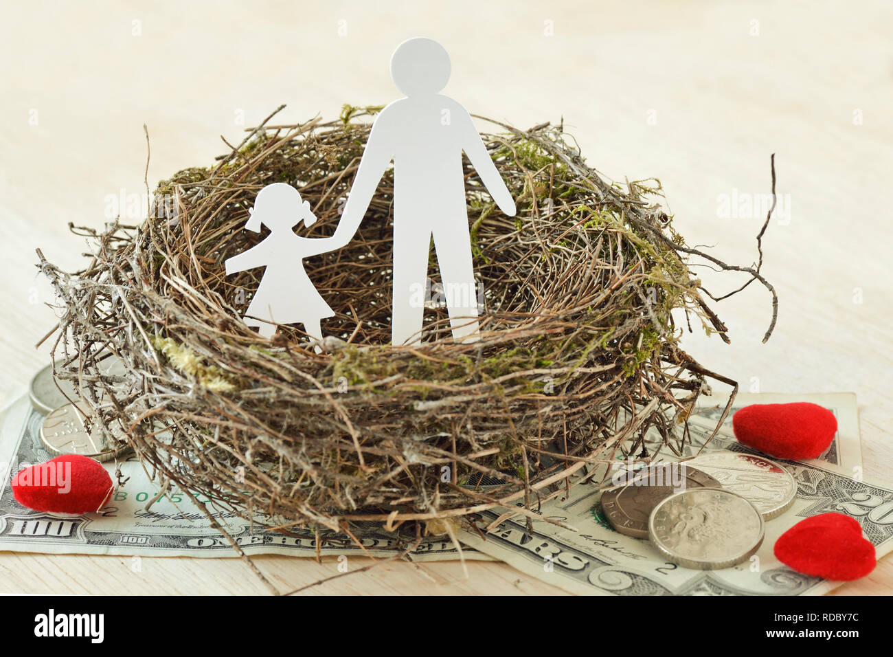 Papier Vater und Tochter im Nest auf Geld und Herzen - Begriff der alleinerziehenden Elternteil Stockfoto