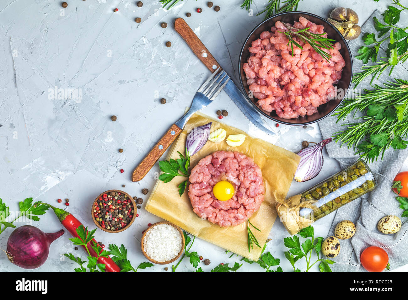 Gesundes Essen, kochen Konzept. Hausgemachte organischen Fleisch Hackfleisch und Tatar mit Eigelb mit Gemüse auf hellen grauen Stein Beton texturiert Stockfoto
