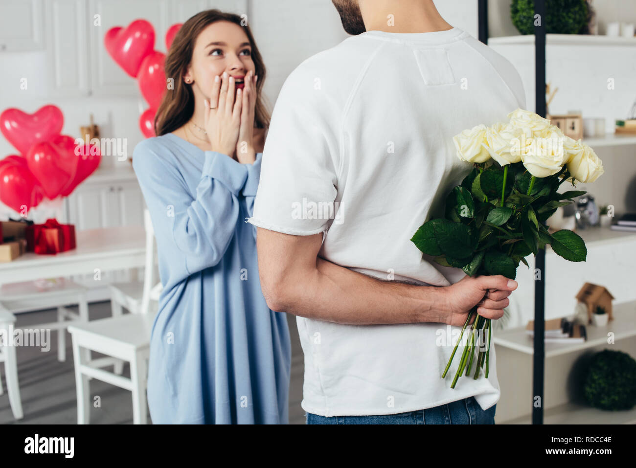 Teilweise mit Blick auf einen jungen Mann mit Blumenstrauß hinter Rücken, während lächelnd Freundin warten auf Überraschung Stockfoto