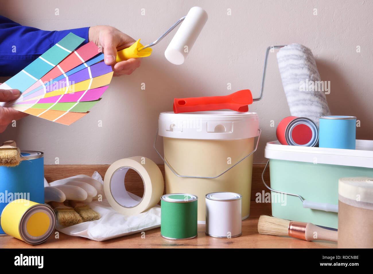 Werkzeuge für Haus auf Parkett mit weißen Wand Hintergrund und Maler Auswahl der Farben auf der Farbkarte. Horizontale Komposition. Vorderansicht. Stockfoto