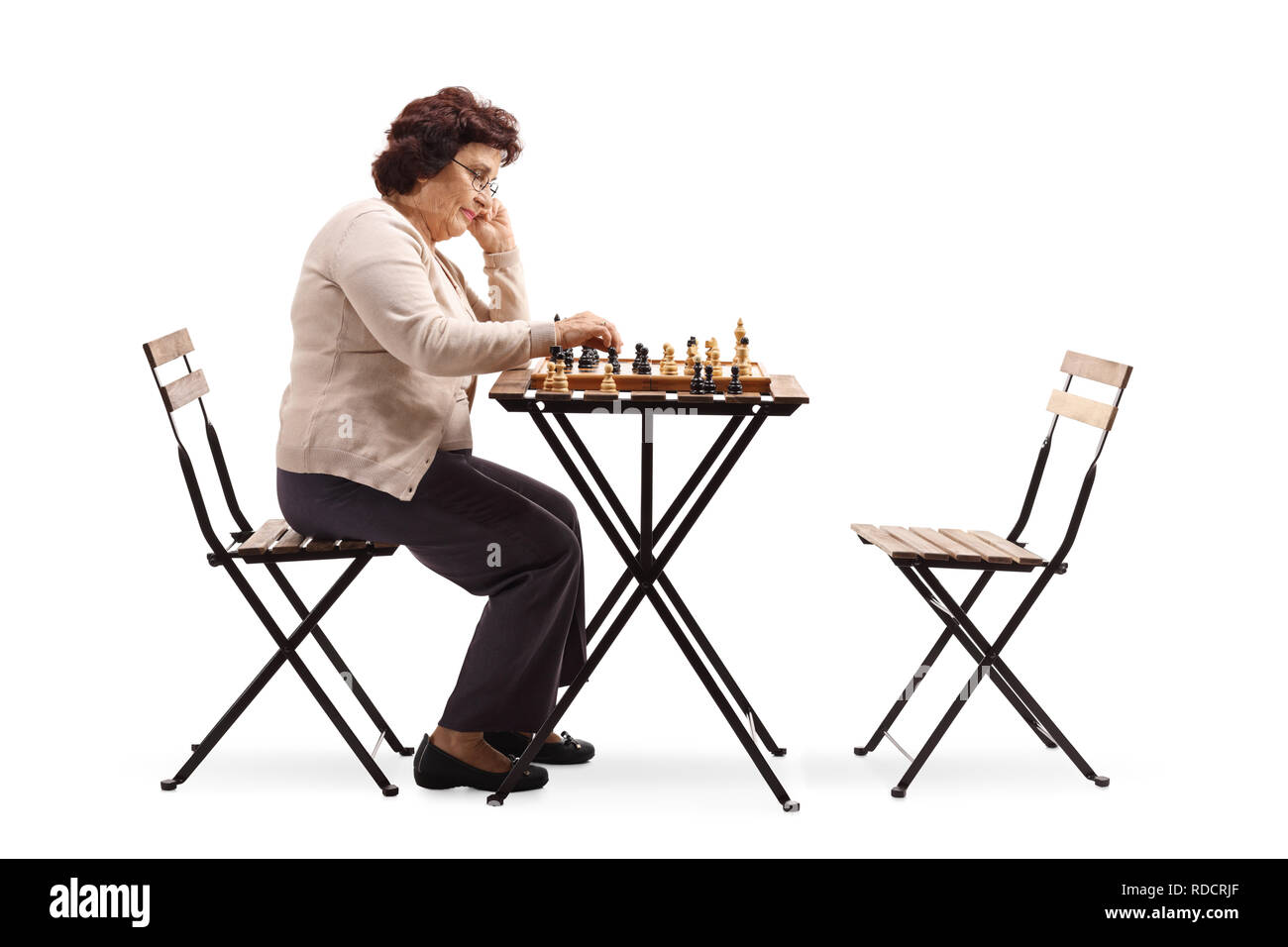 Volle Länge Profil Schuß einer älteren Frau mit einem Schachbrett an einem Tisch in der Chess Abbildung auf weißem Hintergrund suchen Stockfoto